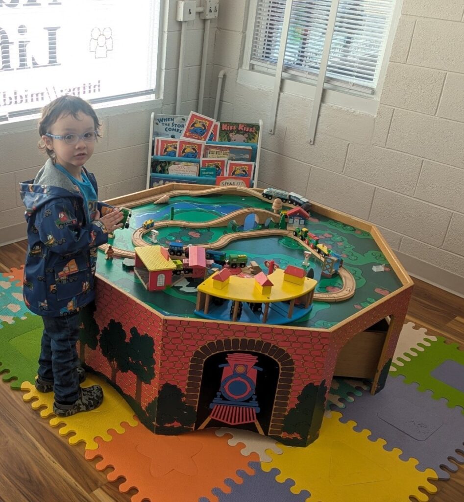 Grayson playing with Train table at Middle Creek Insurance